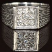 An 18ct white gold ring set with nine diamonds in a square setting, with textured shoulders, 6.2g,