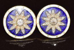 A pair of yellow metal earrings set with blue and white enamel and a raised floral setting set