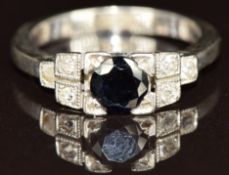 An 18ct white gold ring set with a round cut sapphire and three diamonds to each tiered shoulder,