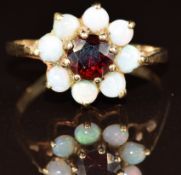 A 9ct gold ring set with a garnet surrounded by opals, 2g, size P
