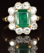 An 18ct gold ring set with an emerald cut emerald of approximately 2.3ct surrounded by ten round cut