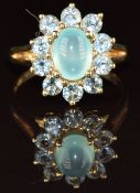 A 9ct gold ring set with a prehnite cabochon surrounded by paste, 3.3g, size M