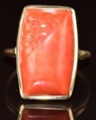 A 9ct gold ring set with a partly carved coral cabochon, 6.3g, size R