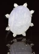An 18ct white gold ring set with a carved lavender jade cabochon depicting a flower surrounded by