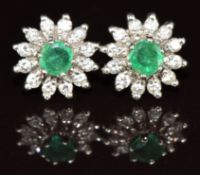 A pair of 18ct white gold earrings each set with a round cut emerald surrounded by diamonds, 3.7g