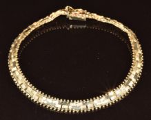 A 14k gold bracelet made up of textured and smooth links, with sphere decoration to the borders,