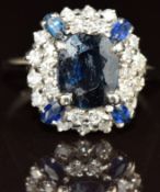 An 18ct gold ring set with an oval cut sapphire surrounded by sapphires and diamonds, 5g, size O