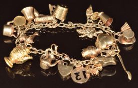 A 9ct gold charm bracelet with twenty one charms including teapot, witch, shoes, key, vase, bucket