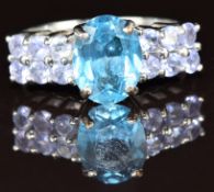 A 9k white gold ring set with an oval cut London blue topaz of approximately 2.5ct and tanzanites,