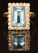 An 18k gold ring set with a baguette cut aquamarine of approximately 2.4ct surrounded by diamonds,
