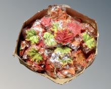 A box containing a large quantity of artificial autumn leaves.