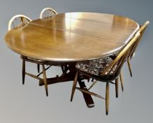 An Ercol solid elm and beech circular pedestal extending dining table fitted with internal leaf