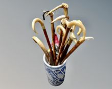 A blue and white ceramic stick pot containing a quantity of vintage walking sticks and umbrellas