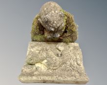 A concrete gargoyle figure together with a further concrete relief plaque.