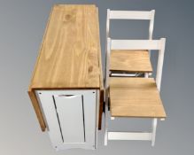 A contemporary pine drop leaf dining table with set of four stow away chairs.