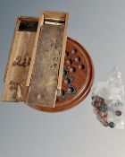 An antique wooden solitaire board with clay marbles, three boxes of bone and wood dominos.