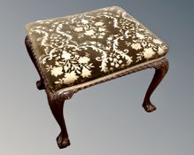 A mahogany dressing table stool on claw and ball feet.