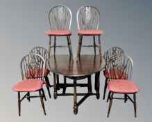 An Ercol stained elm drop leaf dining table together with a set of six wheelback dining chairs.