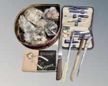 A tin containing a large quantity of vintage buttons, vintage hair clipper, cutlery, manicure set.