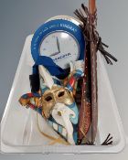 A box containing decorative masks, wall clocks, two machetes in sheaths, three medallions, plaque,