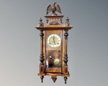 A walnut eight day wall clock with brass and enamel dial, surmounted by an eagle.