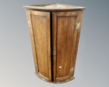 A George III oak double panel door hanging corner cabinet.