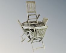 A folding octagonal teak garden table together with a set of four matching folding chairs.