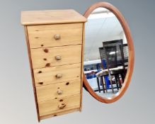 A narrow pine five drawer chest together with an oval pine framed mirror.