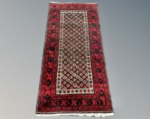 An Afghan long rug on red ground, 180cm by 88cm.