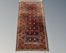 An Afghan rug on rust ground, 181cm by 89cm.