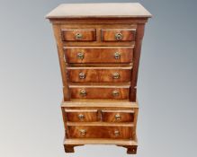 A reproduction mahogany miniature chest of eight drawers.