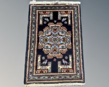 A fringed Caucasian rug with geometric design on blue ground, 110cm by 71cm.