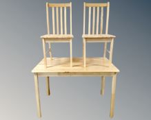 A contemporary pine effect rectangular dining table and two chairs.