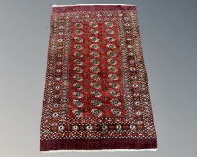 An Afghan Tekke rug on red ground, 191cm by 121cm.