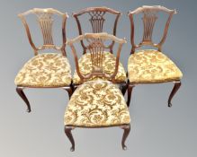 A set of four mahogany dining chairs in gold floral upholstery.