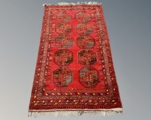 An Afghan Bokhara rug on red ground, 222cm by 126cm.