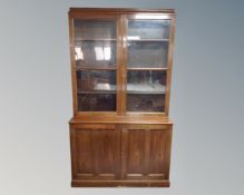 A late Victorian stained pine glazed double door bookcase, fitted with cupboards beneath.