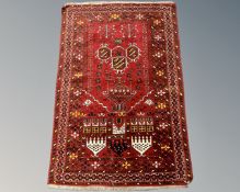 An Afghan/Caucasian prayer rug on red ground, 124cm by 83cm.