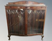 A mahogany serpentine front double door glazed bookcase on claw and ball feet.