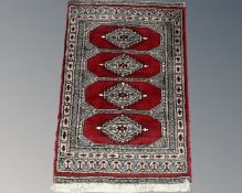 An Afghan design rug on red ground,
