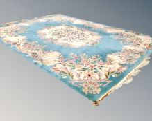 A Chinese fringed embossed carpet on turquoise ground.