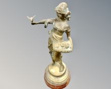 A bronze figure on socle base depicting a lady holding a dove.