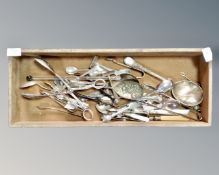 A wooden tray containing antique and later cutlery, sugar tongs, fruit spoons, etc.