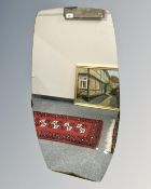 An early 20th century frameless shaped mirror, 65cm by 126cm.