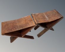 Two vintage folding X-frame stools with tooled leather saddles depicting animals.
