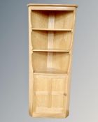 An Ercol elm and beech open corner shelving unit fitted with cupboards below.