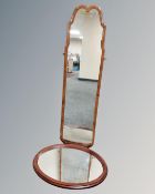 An early 20th century shaped walnut framed hall mirror together with a further oval framed mirror.