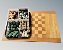 A large wooden chessboard together with three sets of chess pieces.