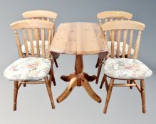 A contemporary pine drop leaf pedestal kitchen table together with four chairs.