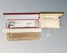 A silver bracelet with heart padlock together with three natural and simulated pearl necklaces,